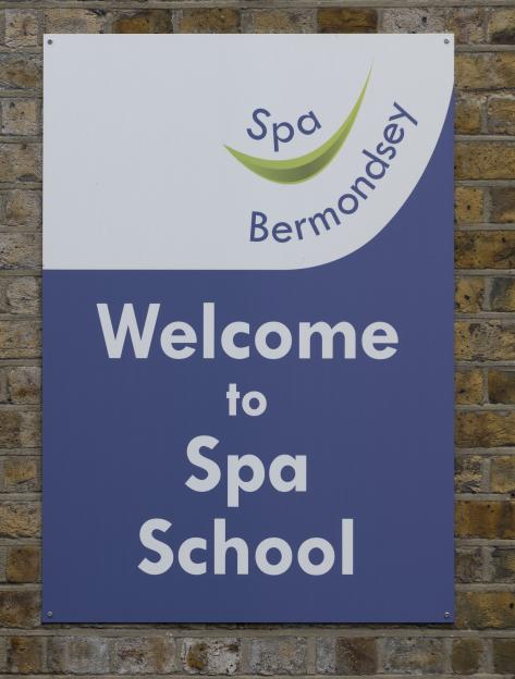 Welcome to Spa School sign on a brick wall.