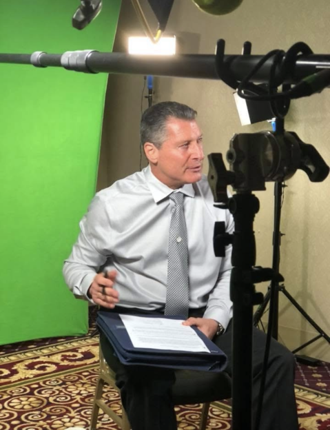 Mafia hitman Larry Mazza sitting in a chair, holding documents.