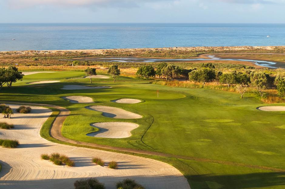 Quinta da Ria golf course with green fairways, sand traps, and the ocean in the background.