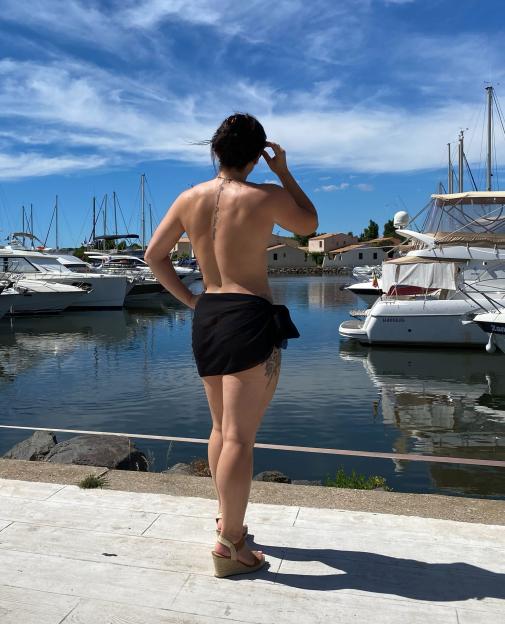 Woman in a sarong facing away from the camera, looking out at a marina.