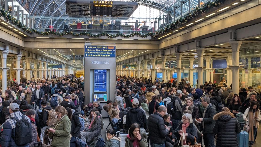 Crowded St Pancras International Station with many people waiting.