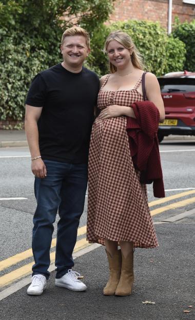 Sam Aston and his pregnant wife Briony Gardner smiling for a photo.