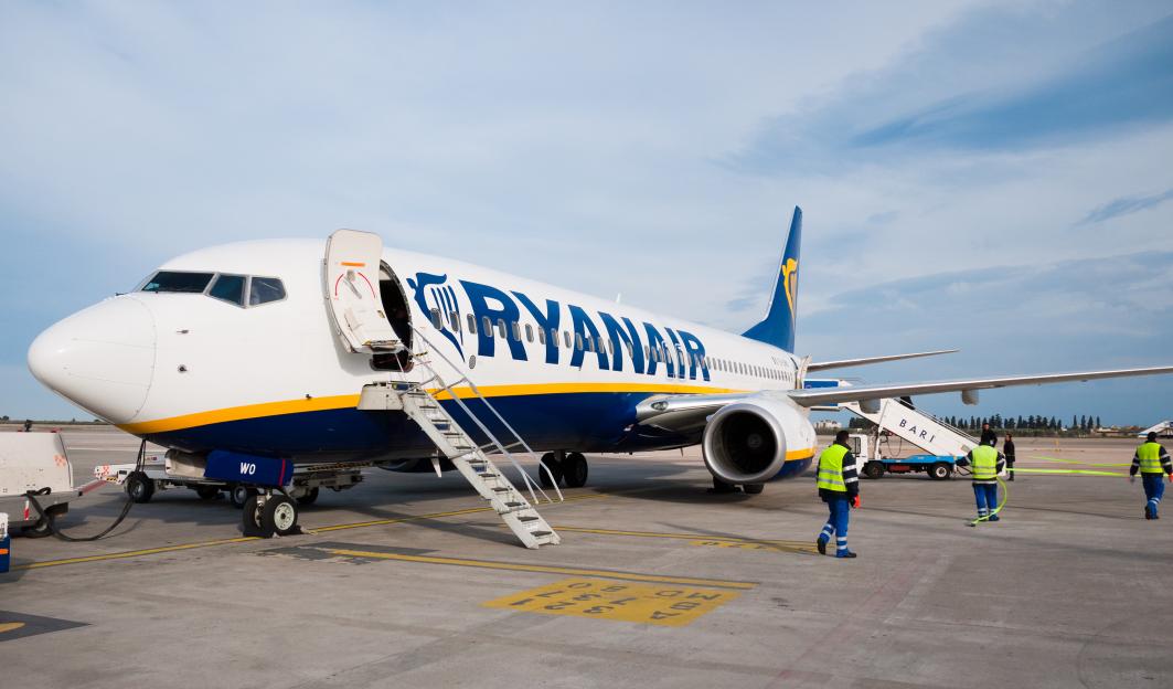 A Ryanair Boeing 737-800 airplane parked at an airport with boarding stairs.