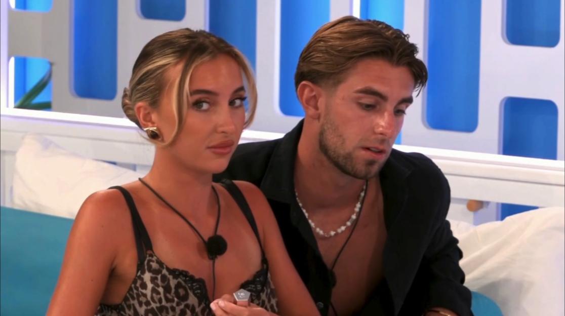 A woman wearing a leopard print top and a man with a beaded necklace.