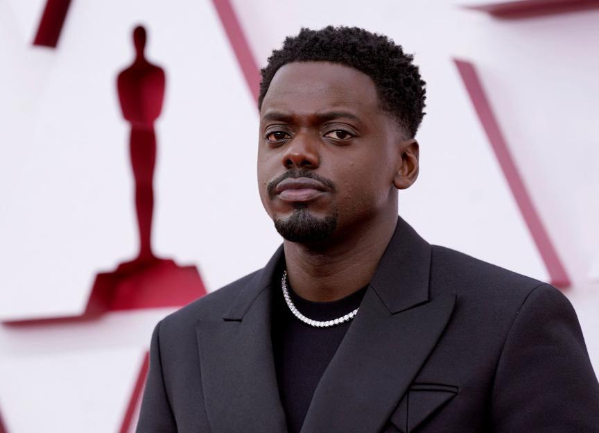 Actor Daniel Kaluuya wearing a dark suit and a diamond necklace, looking at the camera.