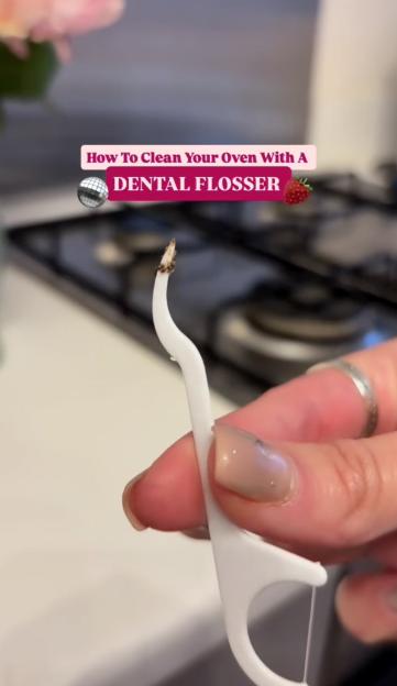 A hand holding a dental flosser with a charred end, demonstrating how to clean an oven.