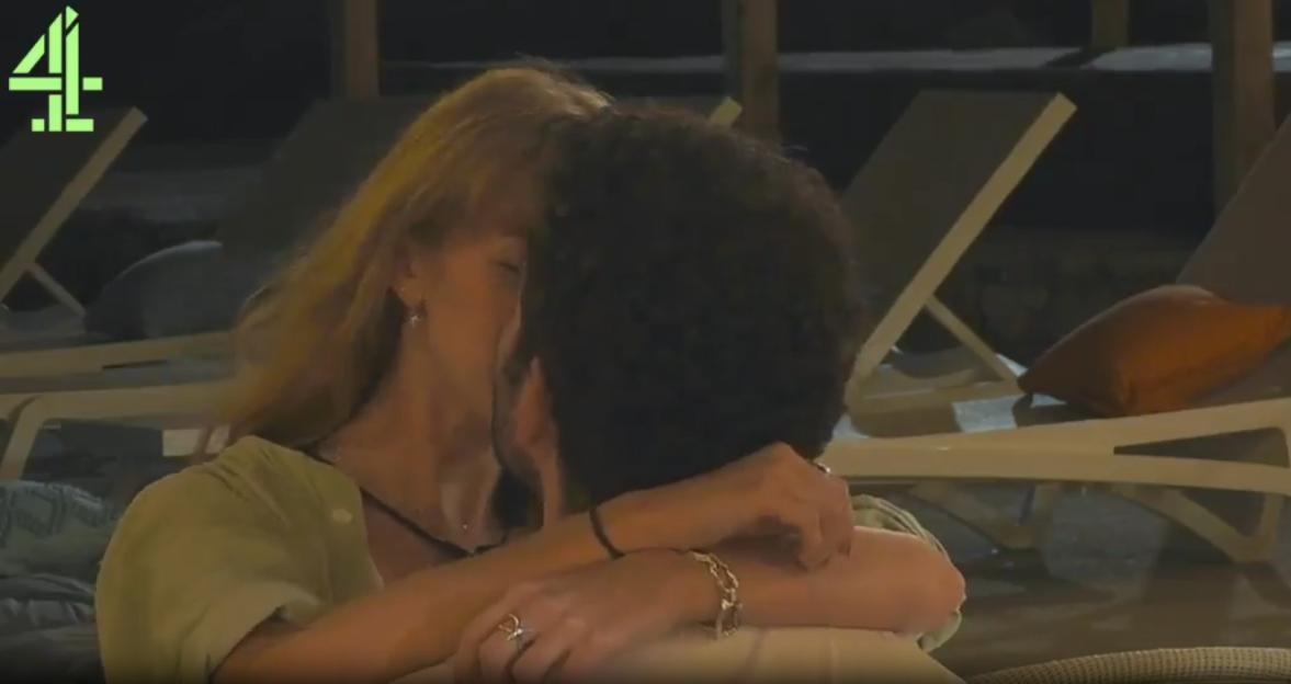 A blonde woman and a dark-haired man kissing passionately, with the woman's arms wrapped around the man.