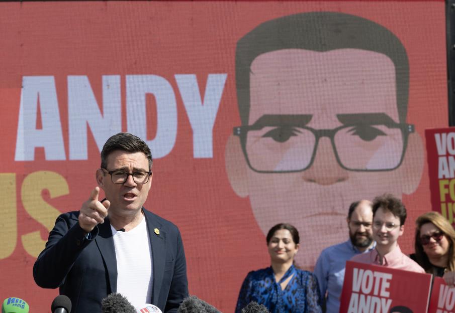 Andy Burnham campaigning, pointing, with a stylized image of his face on a red background.