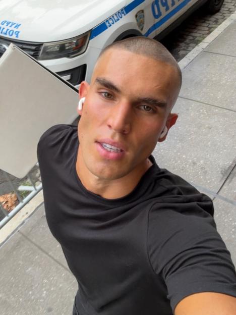 Josh McGregor posing for a selfie in front of a NYPD car.