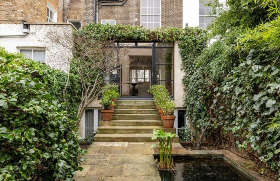 The back of a London house on Ladbroke Grove with an ivy-covered entrance, stone steps, and a pond.