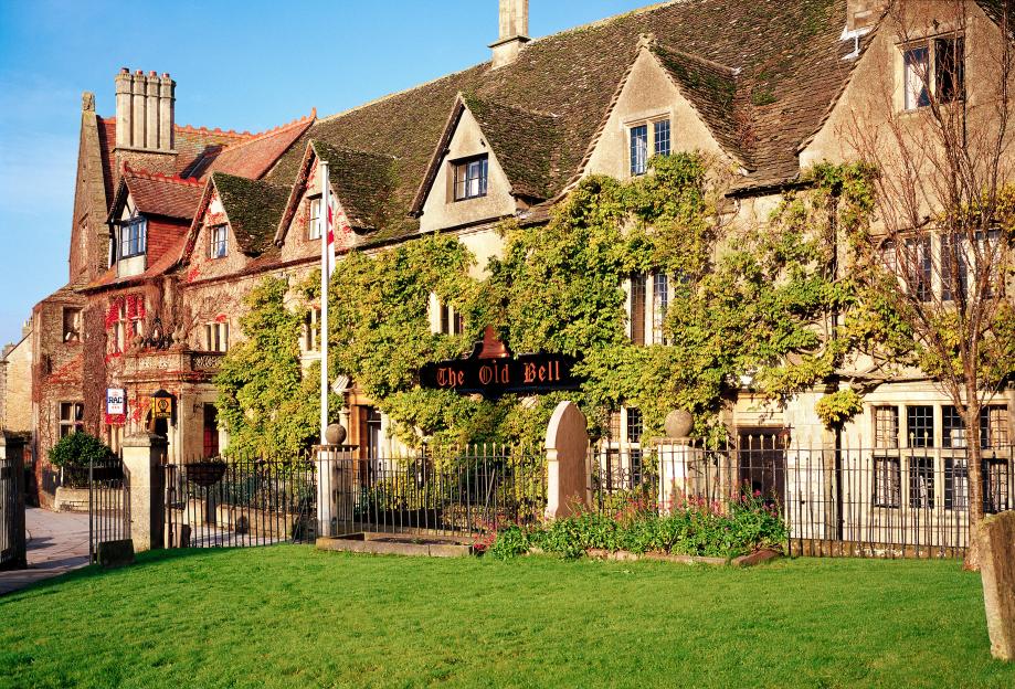 The Old Bell Inn, a historic hotel in Malmesbury, Wiltshire, UK, featuring a stone building covered in ivy and a sign that reads "The Old Bell."