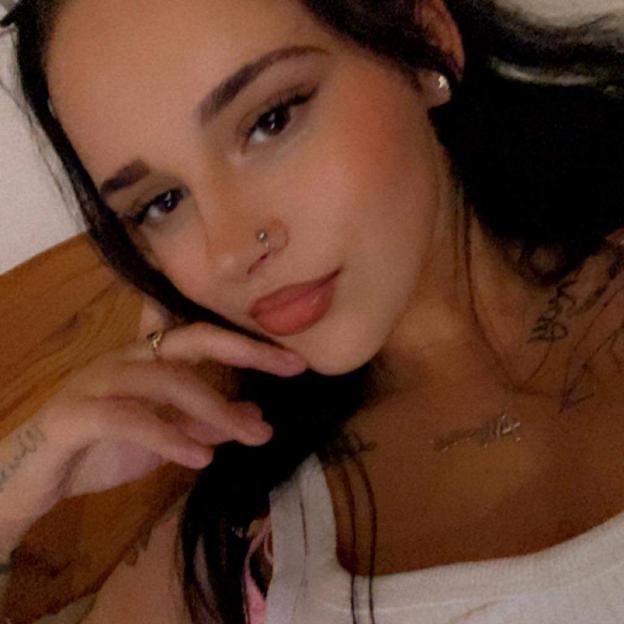 Destiny Harrison, a woman with dark hair, a nose piercing, and tattoos, wearing a white top.