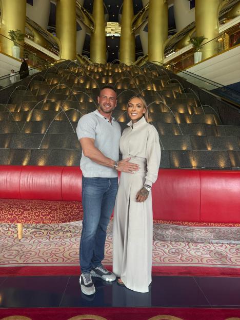 A couple posing in front of a grand waterfall in a lavish hotel.