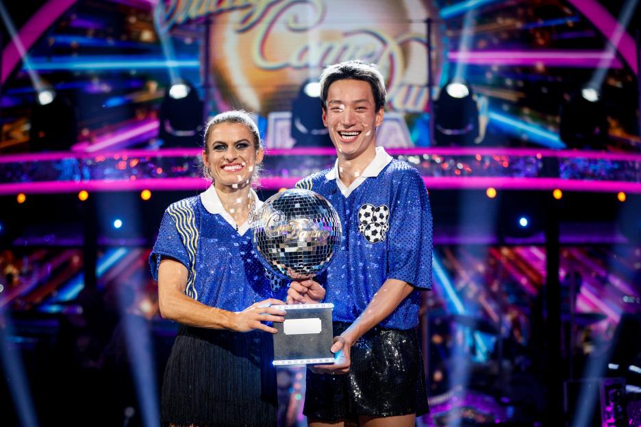Karen Carney and Carlos Gu holding the Strictly Come Dancing trophy.
