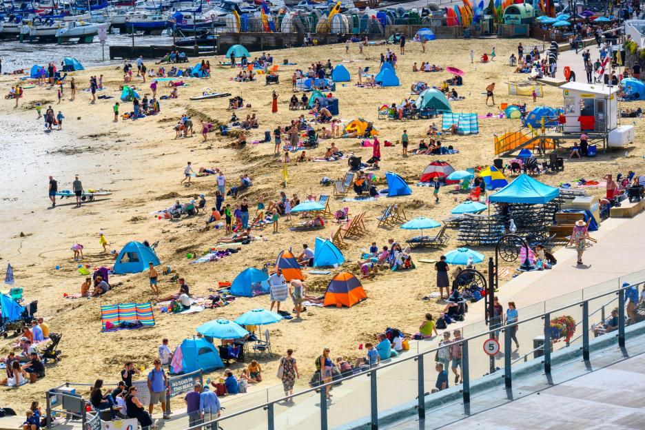 Holidaymakers and families enjoying warm sunny spells on Lyme Regis beach.