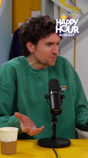 Greg James speaking into a microphone with a coffee cup in front of him.