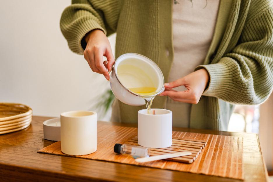 Woman pouring melted wax into a candle container.