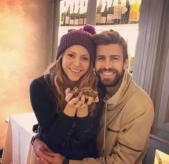 Shakira and Gerard Pique smiling, with Shakira holding two truffles in her hands.