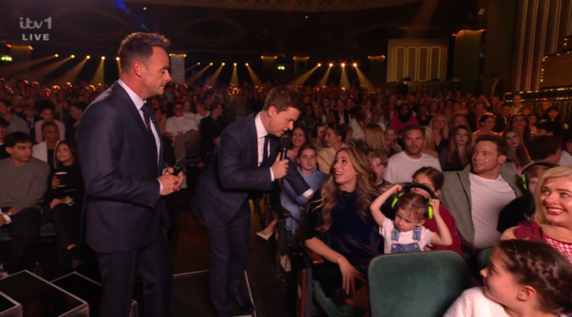 Stacey Solomon, holding a child wearing headphones, being interviewed by Declan Donnelly at Britain's Got Talent.
