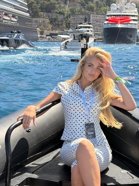 Princess Andre in a white polka dot outfit posing on a boat in Monaco.