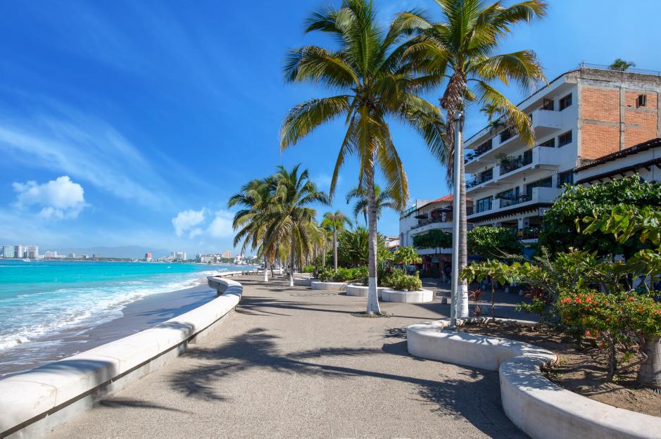 Wide shot couple toasting with mimosas on beach at tropical resort