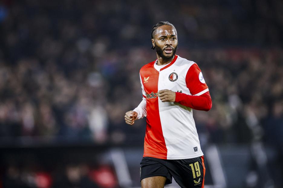 A man wearing a red and white soccer jersey with the number 19 on his shorts.