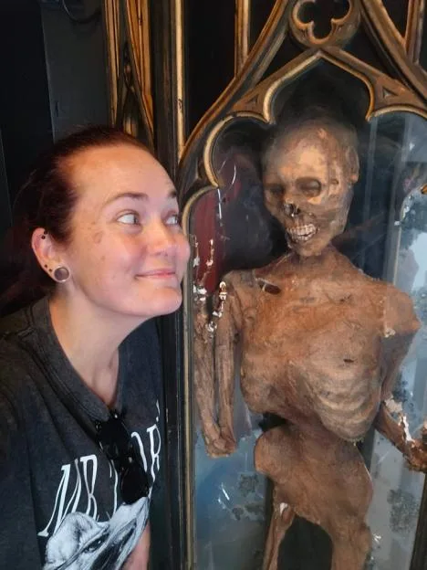 Sophie Minot poses next to a skeleton inside a display case at Halloween Horror Nights.