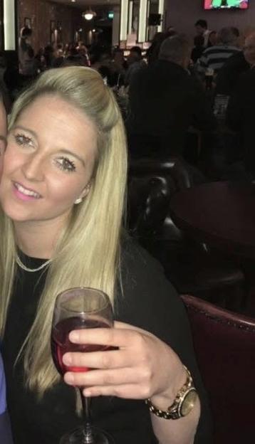 Marnie Dillon, with long blonde hair, smiling and holding a glass of wine in a dark room.