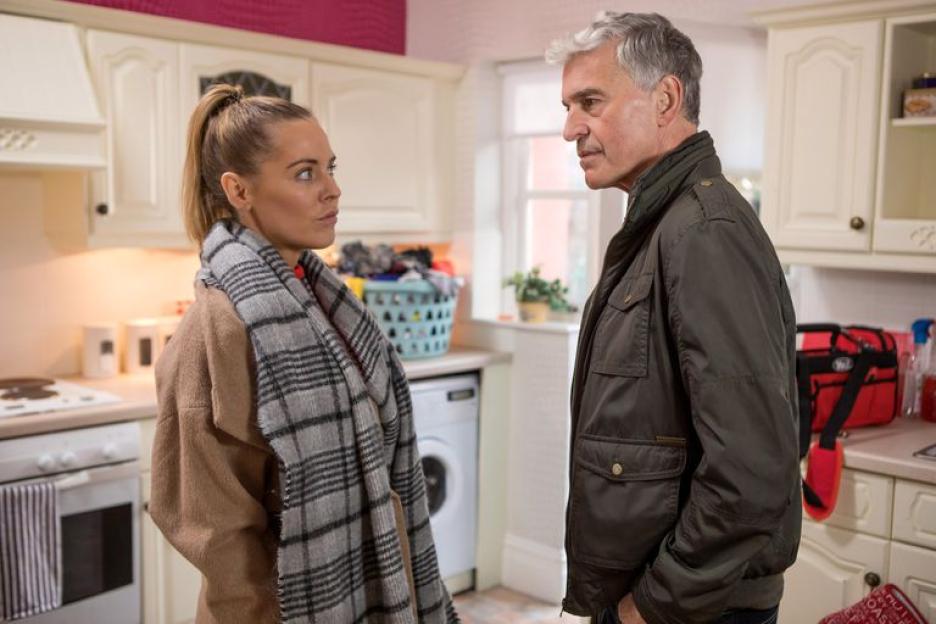 Cindy Cunningham, with a serious expression, facing another person in a kitchen.