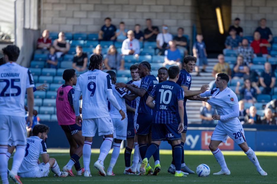 Football players from Millwall and Bolton Wanderers in a confrontation on the field during an EFL Sky Bet Championship match.