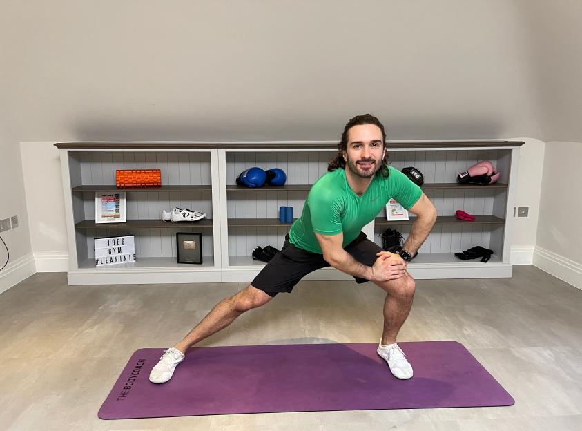 Joe Wicks, "The Body Coach," performing a lunge on a purple exercise mat during an online fitness class.