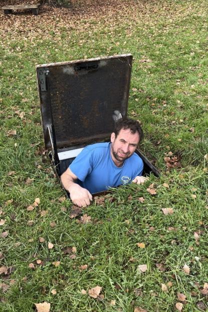 Dave Billing emerging from the hatch of a bunker he built in his garden.