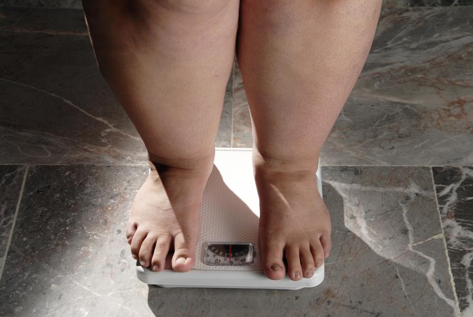 A barefoot person stands on a weight scale.