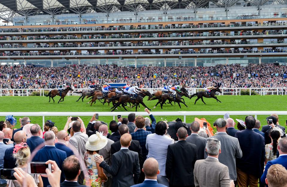 Racegoers watching a horse race from the Village Enclosure at Royal Ascot.