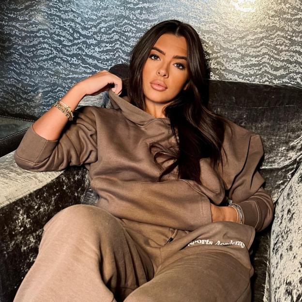 Gemma Owen wearing a brown loungewear set while sitting on a couch.