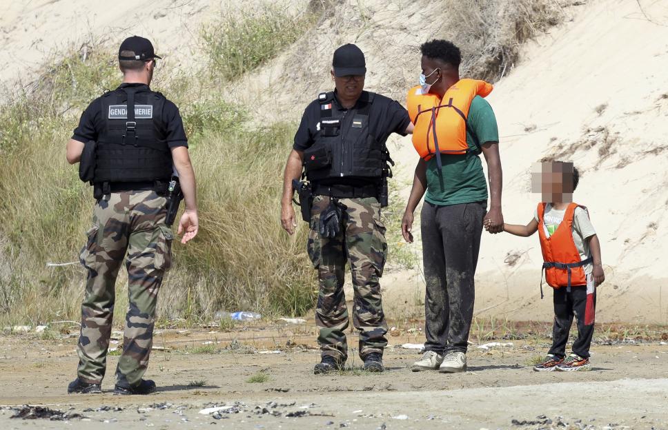 French Gendarmerie officers detain a migrant man and a child at Hardelot Beach.