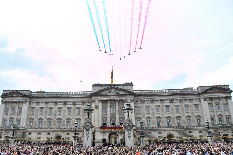 The Royal Air Force Red Arrows fly in formation over Buckingham Palace, leaving trails of red, white, and blue smoke during Trooping the Colour.