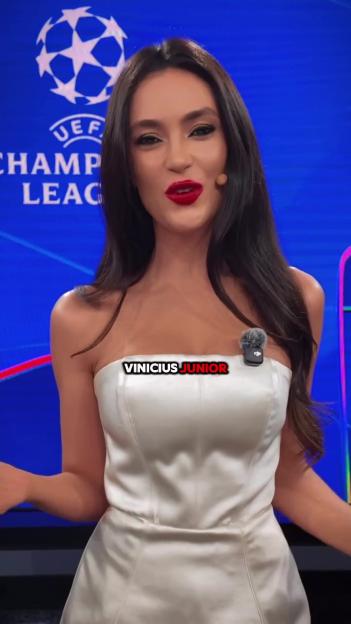 A woman in a white dress stands in front of a blue background with the UEFA Champions League logo.