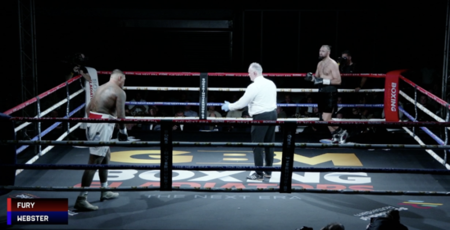 Two boxers and a referee in a boxing ring with "FURY" and "WEBSTER" displayed on screen.