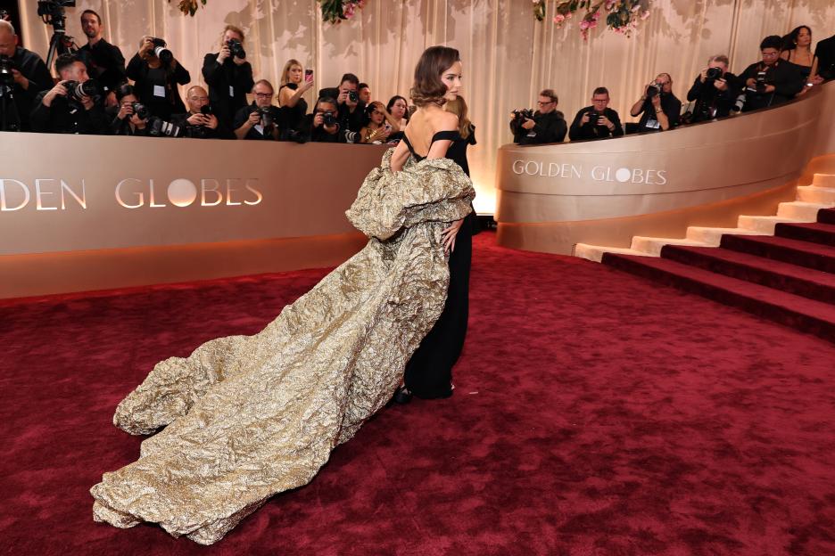 Maura Higgins in a black dress with an elaborate gold train on the red carpet at the Golden Globe Awards.