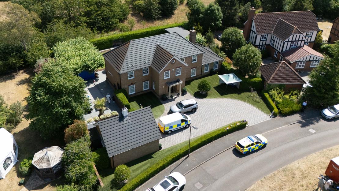 Aerial view of the scene at a house on Carnoustie Drive, Great Denham, with multiple police vehicles present.