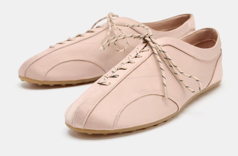 Pair of nude-colored lace-up sneakers.