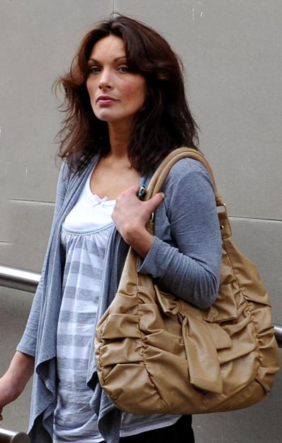 Sarah Aspin holding a large tan handbag.