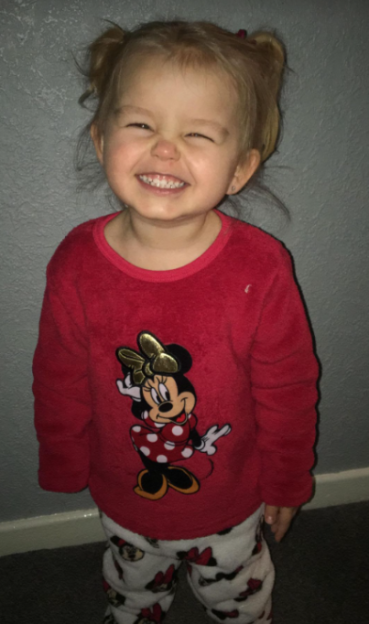 Smiling toddler Louisianna wearing red Minnie Mouse pajamas.