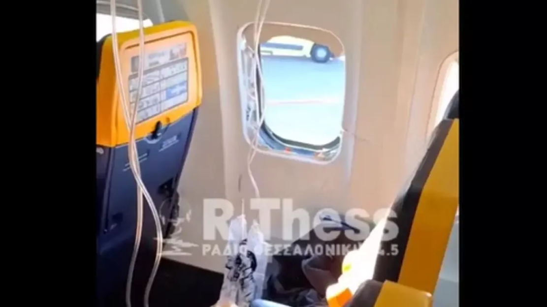 Broken airplane window with oxygen masks deployed.