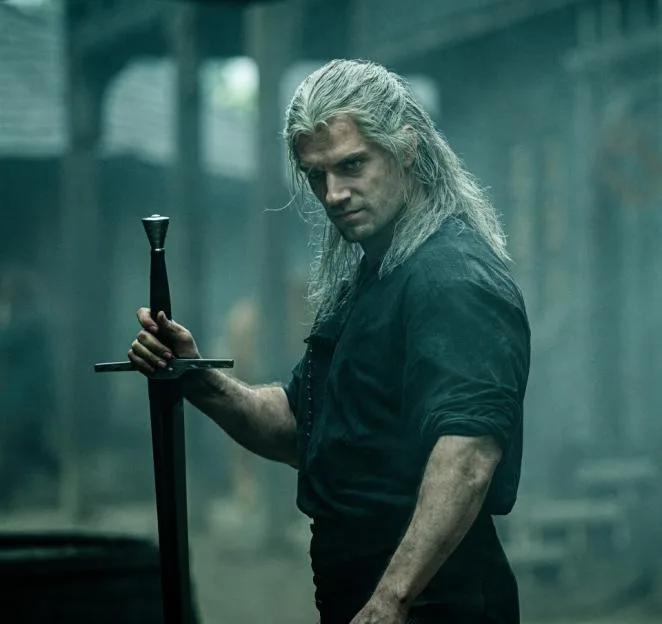 Henry Cavill as Geralt of Rivia holding a sword in The Witcher.