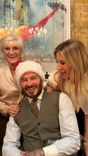 David Beckham in a Santa hat, laughing with his mother Sandra and sister Joanne.