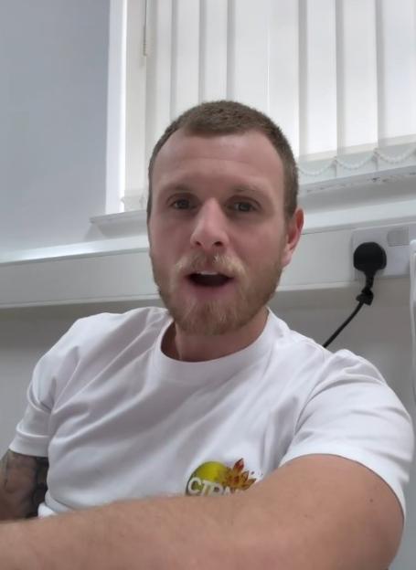A man in a white t-shirt speaking to the camera.