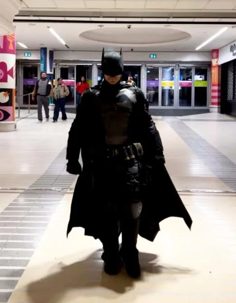 A person in a Batman costume stands in a shopping mall.
