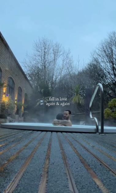 Davide and Keye embracing in a hot tub.